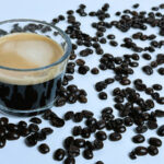 Cận cảnh tách espresso nóng hổi nghi ngút khói, xung quanh là những hạt cà phê rang thơm lừng, thể hiện sự quan tâm và tình yêu thương của người bà.