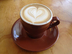 Hình ảnh tách cappuccino đẹp mắt với hình trái tim trên lớp bọt, thể hiện sự tinh tế và ấm áp của Sanji
