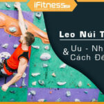 Vận động viên leo núi nhân tạo trong nhà với trang phục bảo hộ đầy đủ.